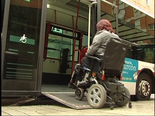 UNa señora en silla de ruedas accede a un autobús a través de una rampa