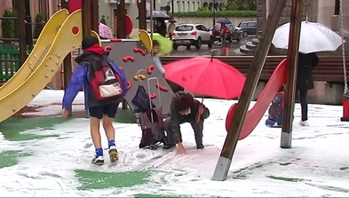 Unos niños juegan con el granizo caído en un parque de Oviedo 