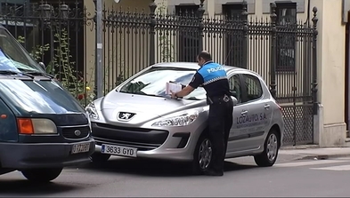 Un Policía Local multando un coche mal estacionado