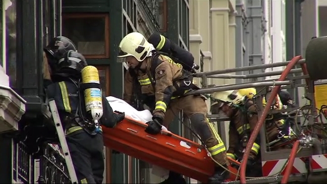 Los bomberos trasladan el cuerpo de uno de los bomberos tras el derrumbe del edificio incendiado