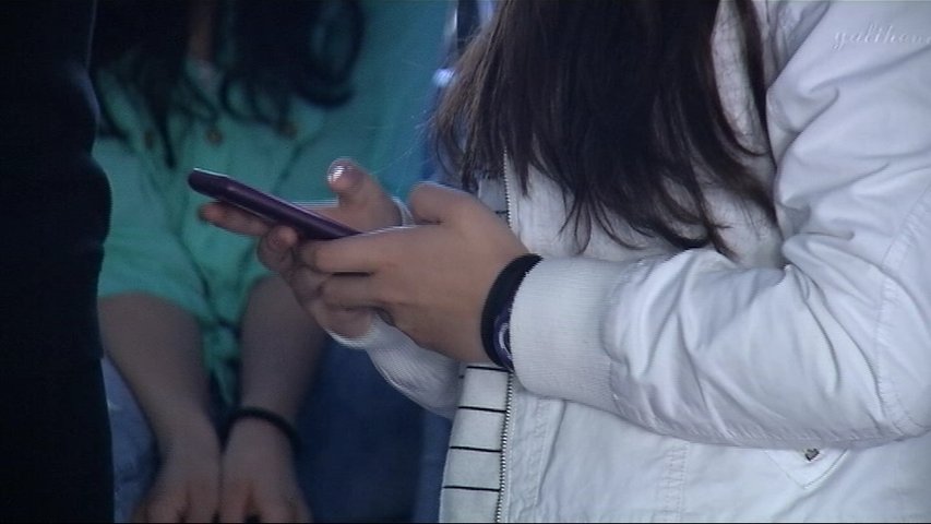 Una niña mira su smartphone en el colegio