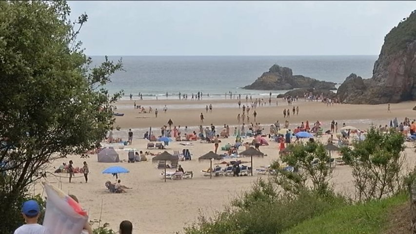 Playa con bastante gente en un día nublado de verano en Asturias