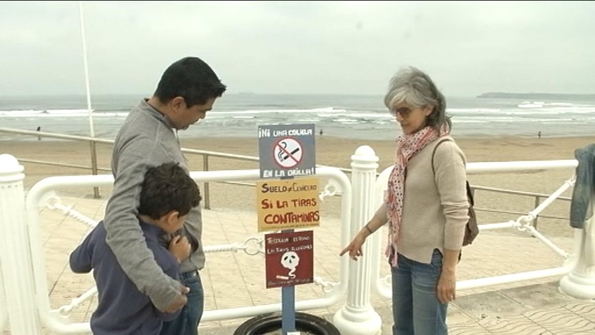 Familia con un niño frente al cártel de 'playas sin humo' en el arenal de Salinas